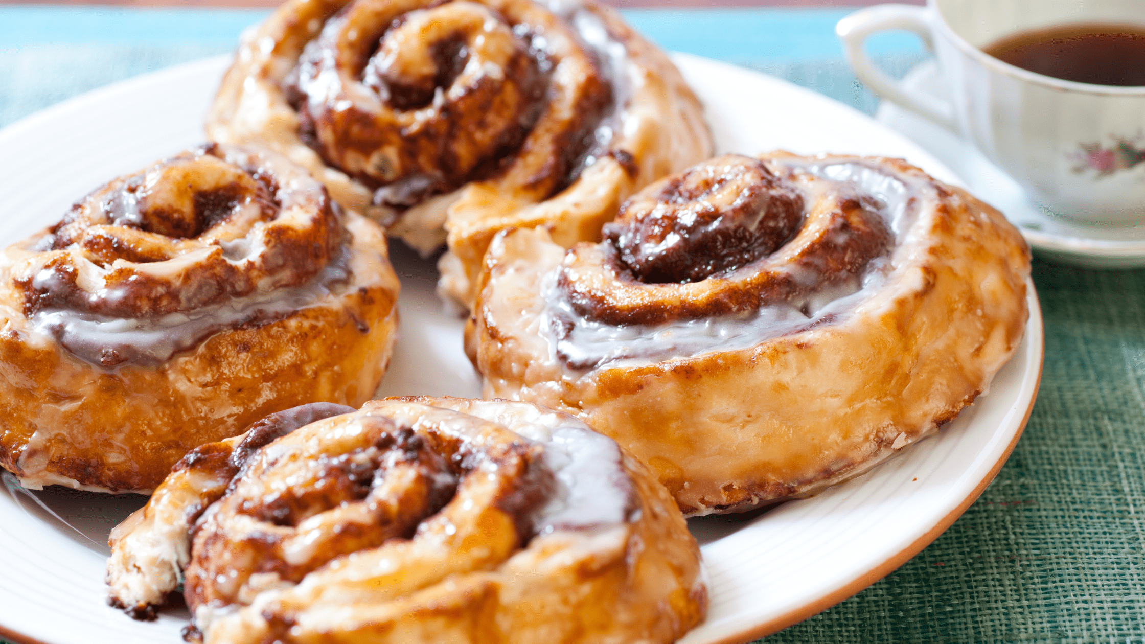 a plate of cinnamon rolls and a china teacup
