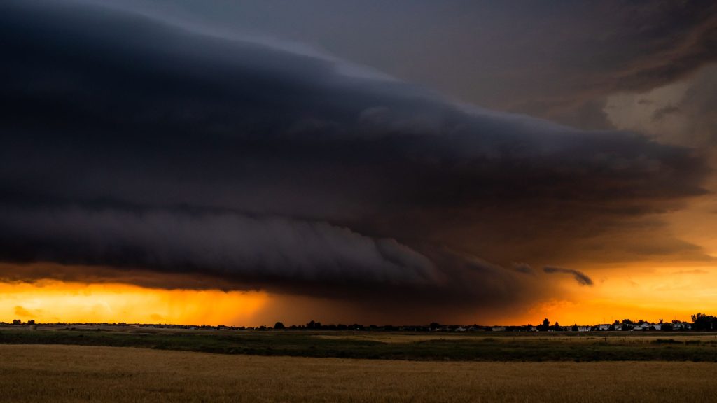 dark thunderstorm cloud in the distance over a yellow field