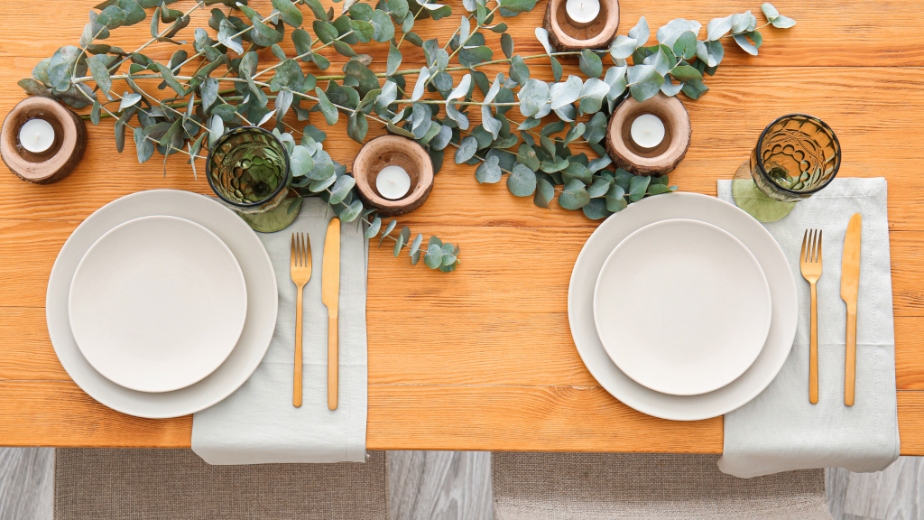 wooden table set for fancy dinner with eucalyptus and candle centrepiece