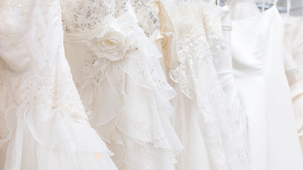 row of white wedding dresses hanging on a rack