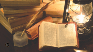 An open Bible on a wooden desk with a feather pen and ancient writings to illustrate writing tips from the Bible
