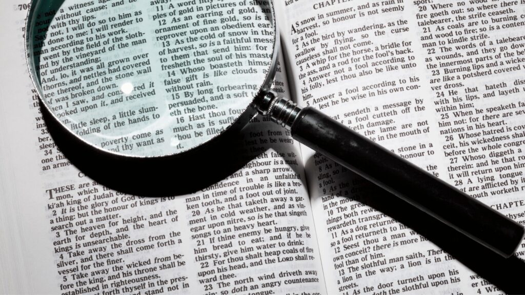 A magnifying glass on top of an open Bible to show the benefit of reading a book of the Bible in one sitting
