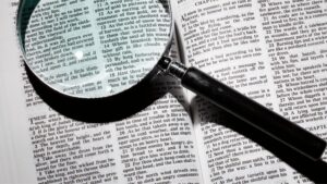 A magnifying glass on top of an open Bible to show the benefit of reading a book of the Bible in one sitting