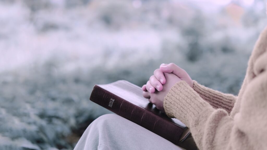 A Christian woman sitting outside with a Bible in her lap when hope seems far away and she wants to know Jeremiah 29:11 meaning in context