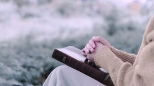 A Christian woman sitting outside with a Bible in her lap when hope seems far away and she wants to know Jeremiah 29:11 meaning in context