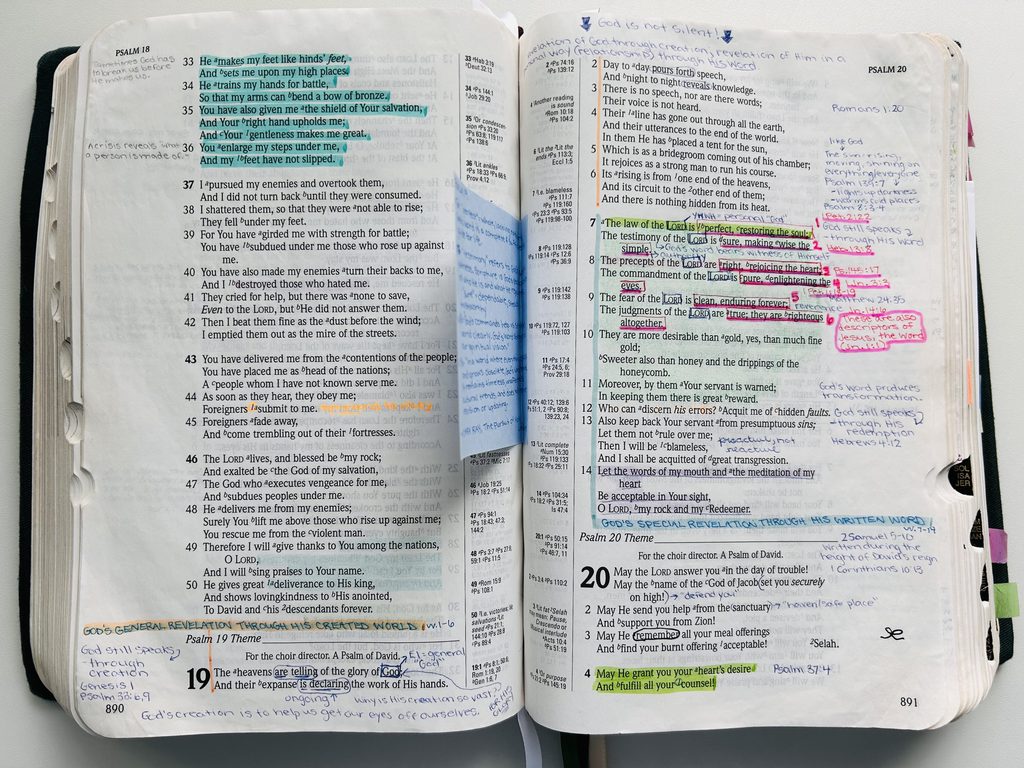 An open Bible with handwritten notes in the margins and highlighted verses