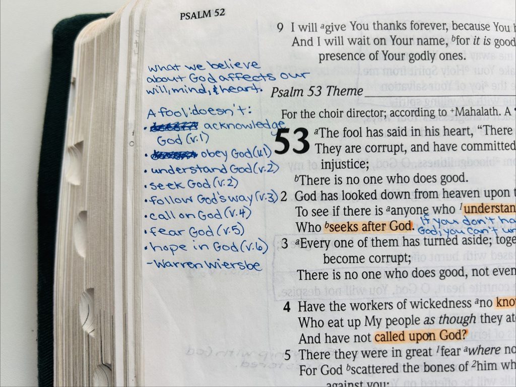 An open Bible with handwritten notes in the margin, including scribbled out words