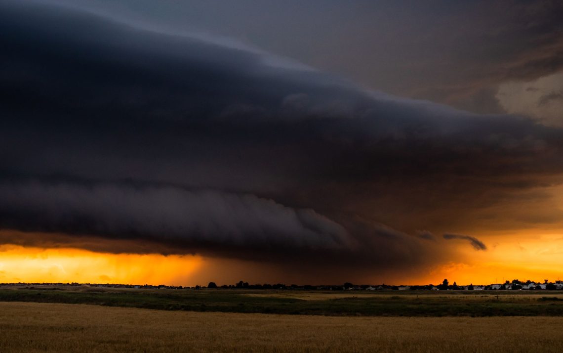 dark thunderstorm cloud in the distance over a yellow field