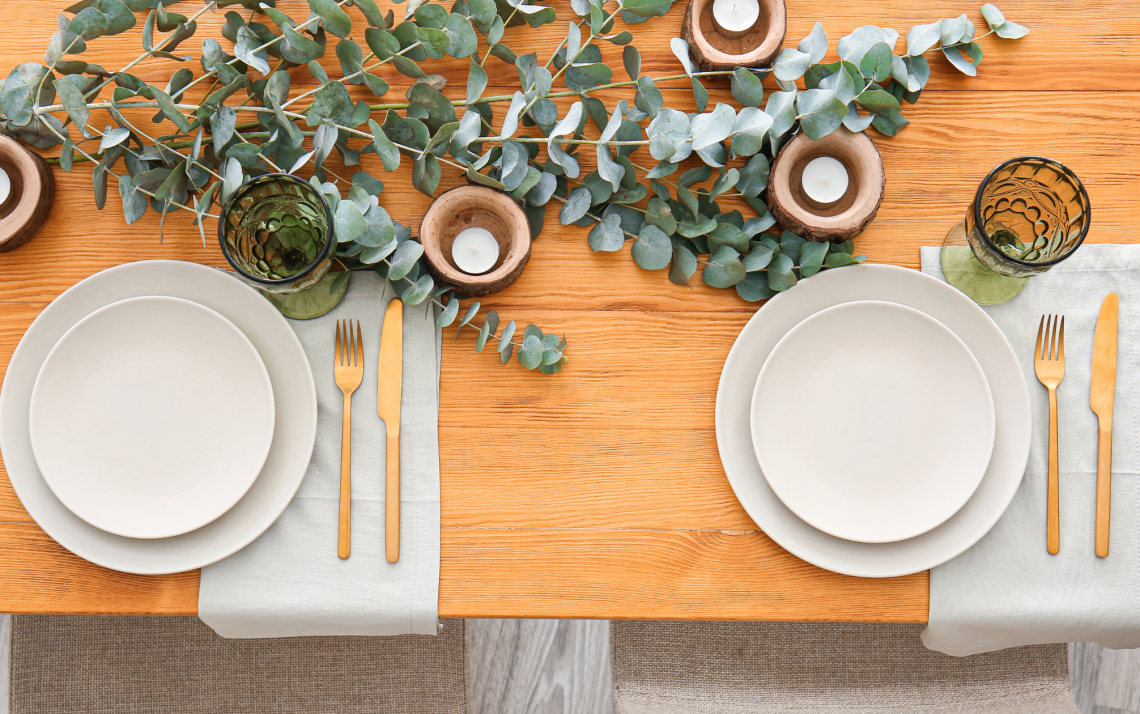 wooden table set for fancy dinner with eucalyptus and candle centrepiece