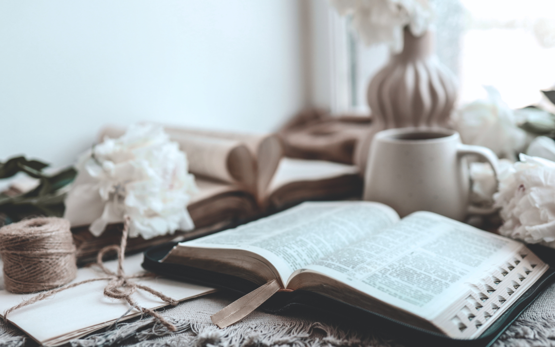 A sunlit kitchen table cluttered with projects but with an open Bible to illustrate how to build consistent spiritual habits