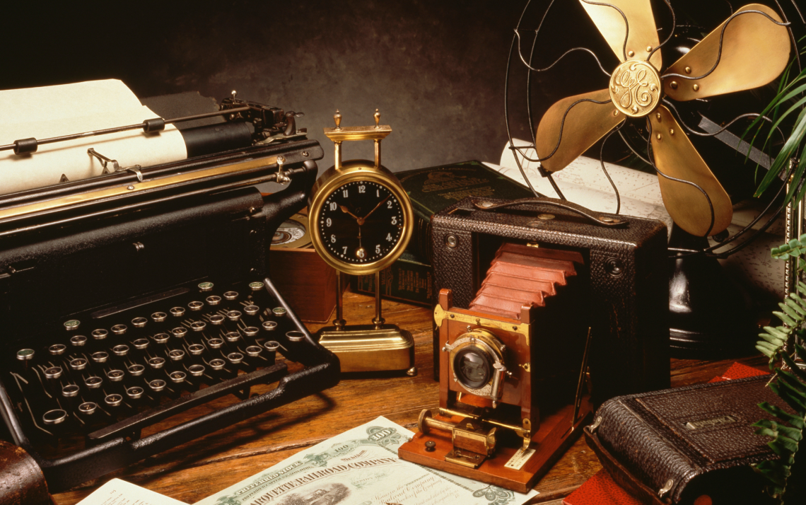 a vignette of antique items including a camera, clock, and typewriter