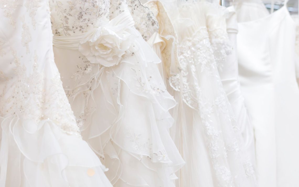 row of white wedding dresses hanging on a rack